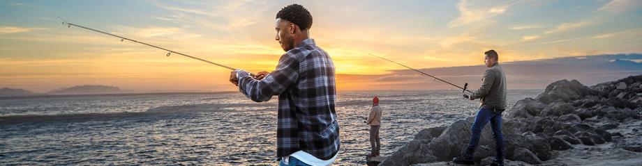 Three anglers fishing from a rocky jetty at sunset.
