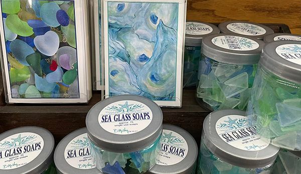Collection of sea glass soaps in glass containers with lids and sea glass note cards.