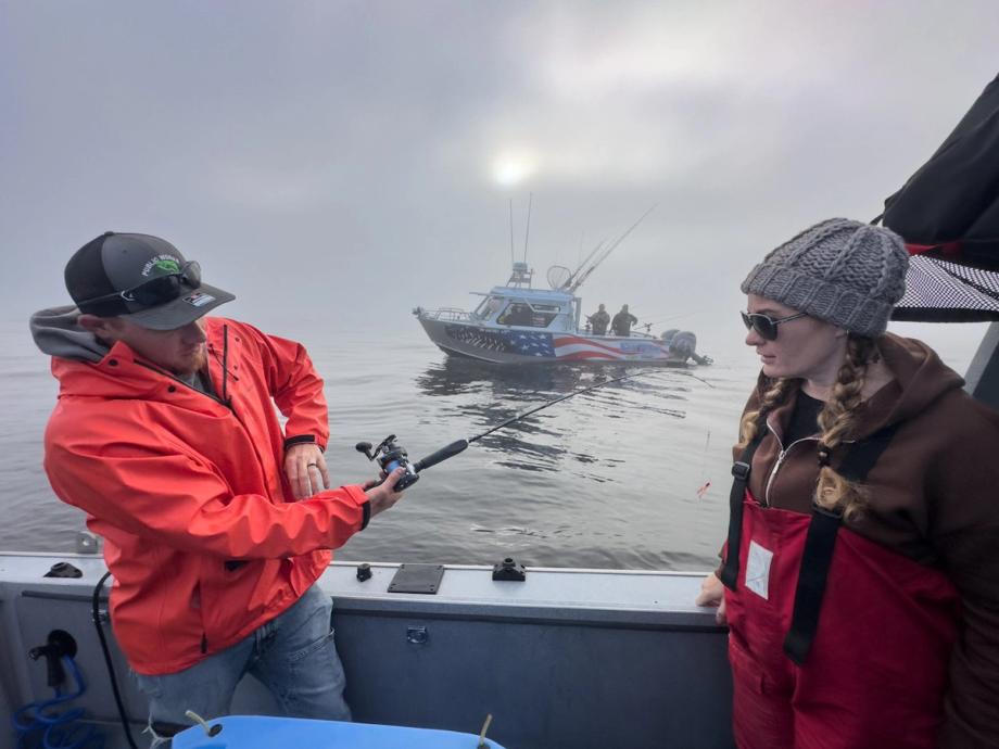 Two anglers in rain gear fish from a charter boat on a foggy morning off Oregon’s Adventure Coast, with a second fishing vessel visible in the misty background.