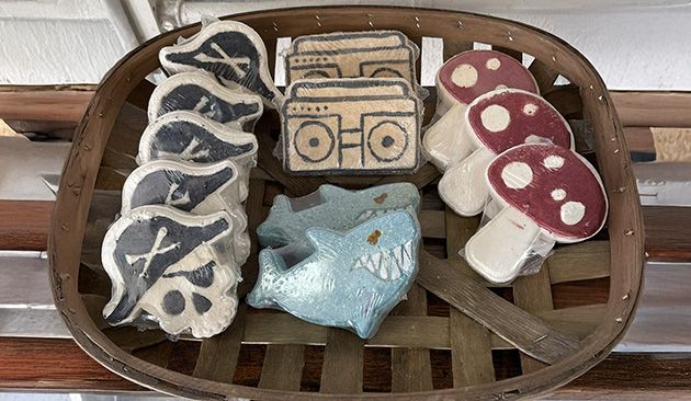 A basket of handmade soaps, including pirate skulls, cassette players, a shark, and mushrooms.