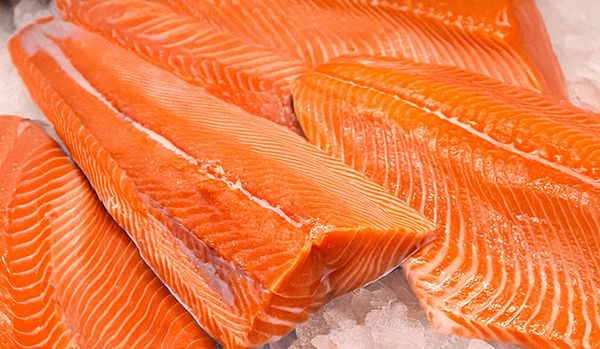 Fresh wild-caught salmon fillets on ice, vibrant orange with rich marbling.