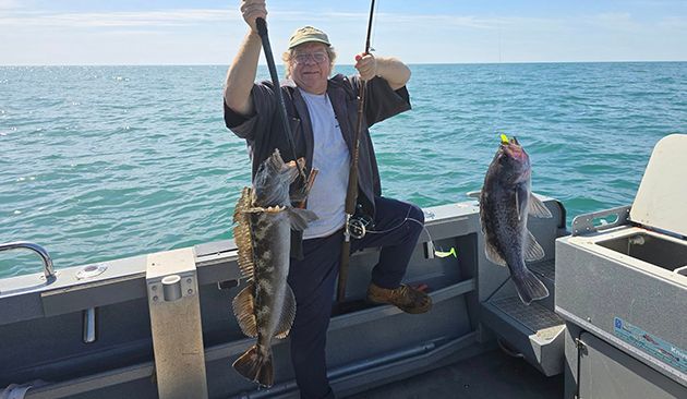 Fisherman holding two poles, each with a fish on the line.