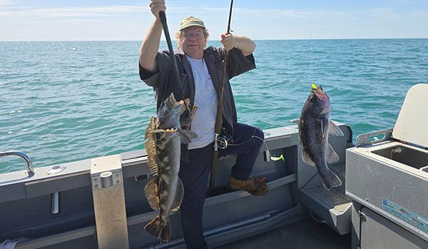 Fisherman holding two poles, each with a fish on the line.
