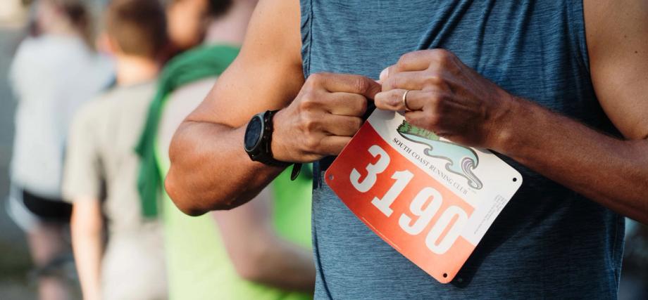 A runner pins on a South Coast Running Club race bib numbered 3190 before the Circle the Bay run.