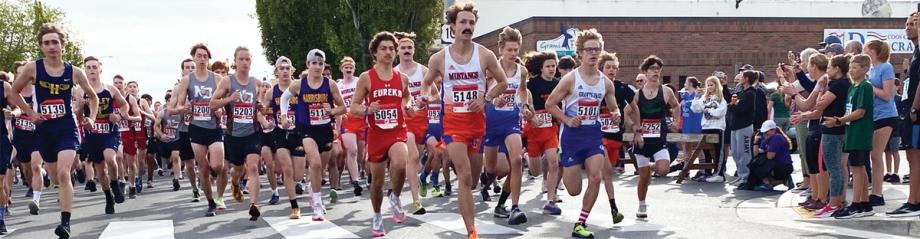 A large group of runners sprints from the starting line past cheering spectators at the Prefontaine Memorial Run.