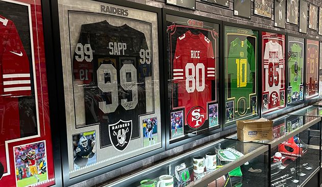 Wall display of framed vintage football jerseys and sports memorabilia in glass cases.
