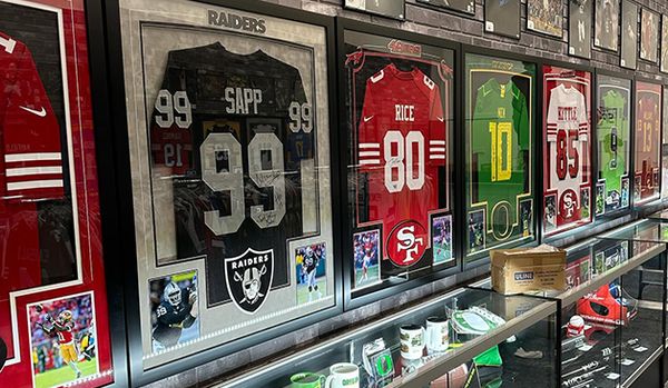 Wall display of framed vintage football jerseys and sports memorabilia in glass cases.