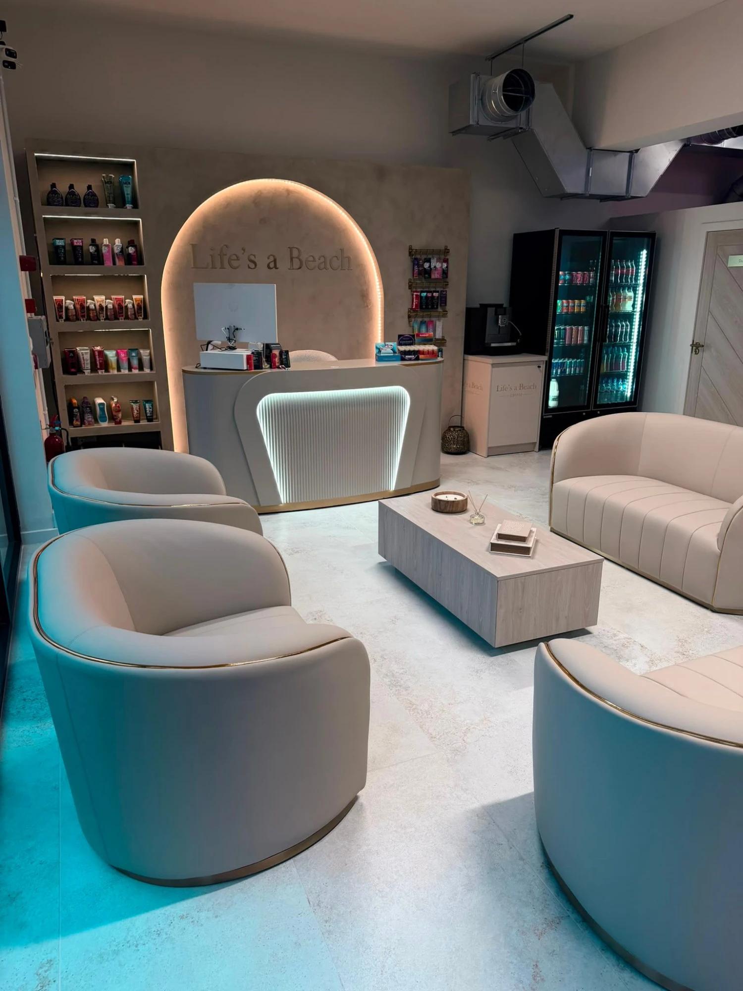Life’s a Beach salon interior — cream lounge seating and backlit reception arch