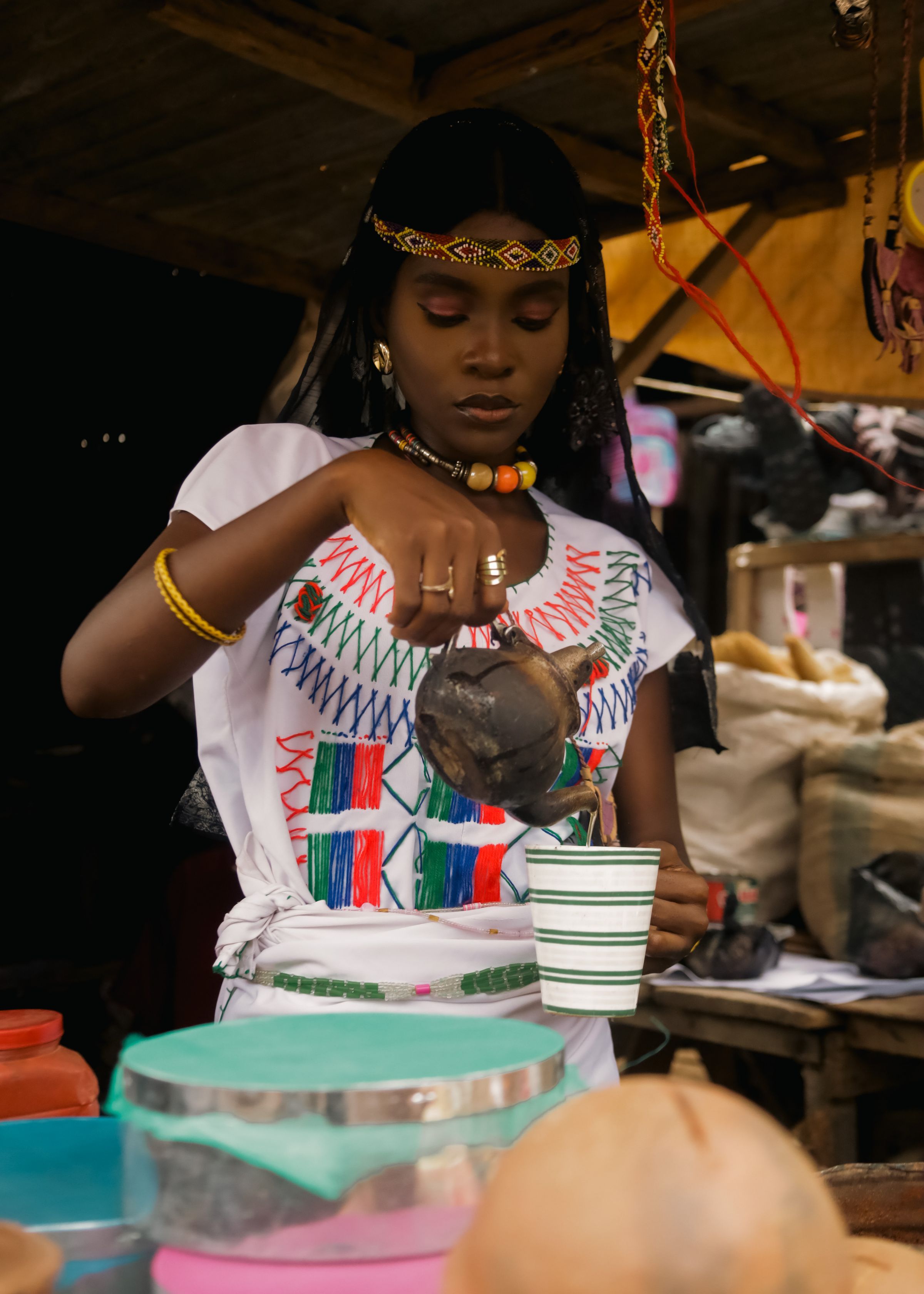 Woman in traditional Ethiopian dress pouring coffee from a jebena during a coffee ceremony