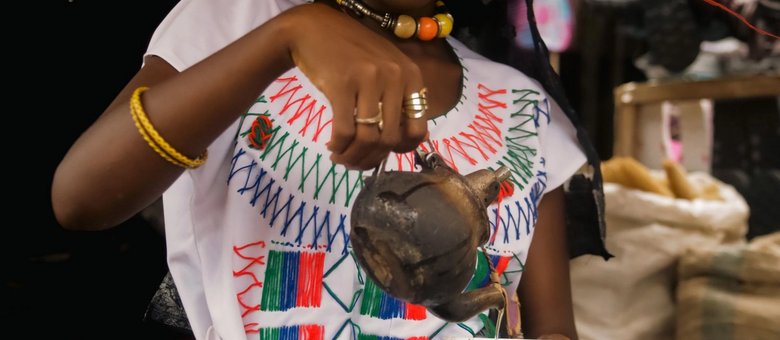 Woman in traditional Ethiopian dress pouring coffee from a jebena during a coffee ceremony