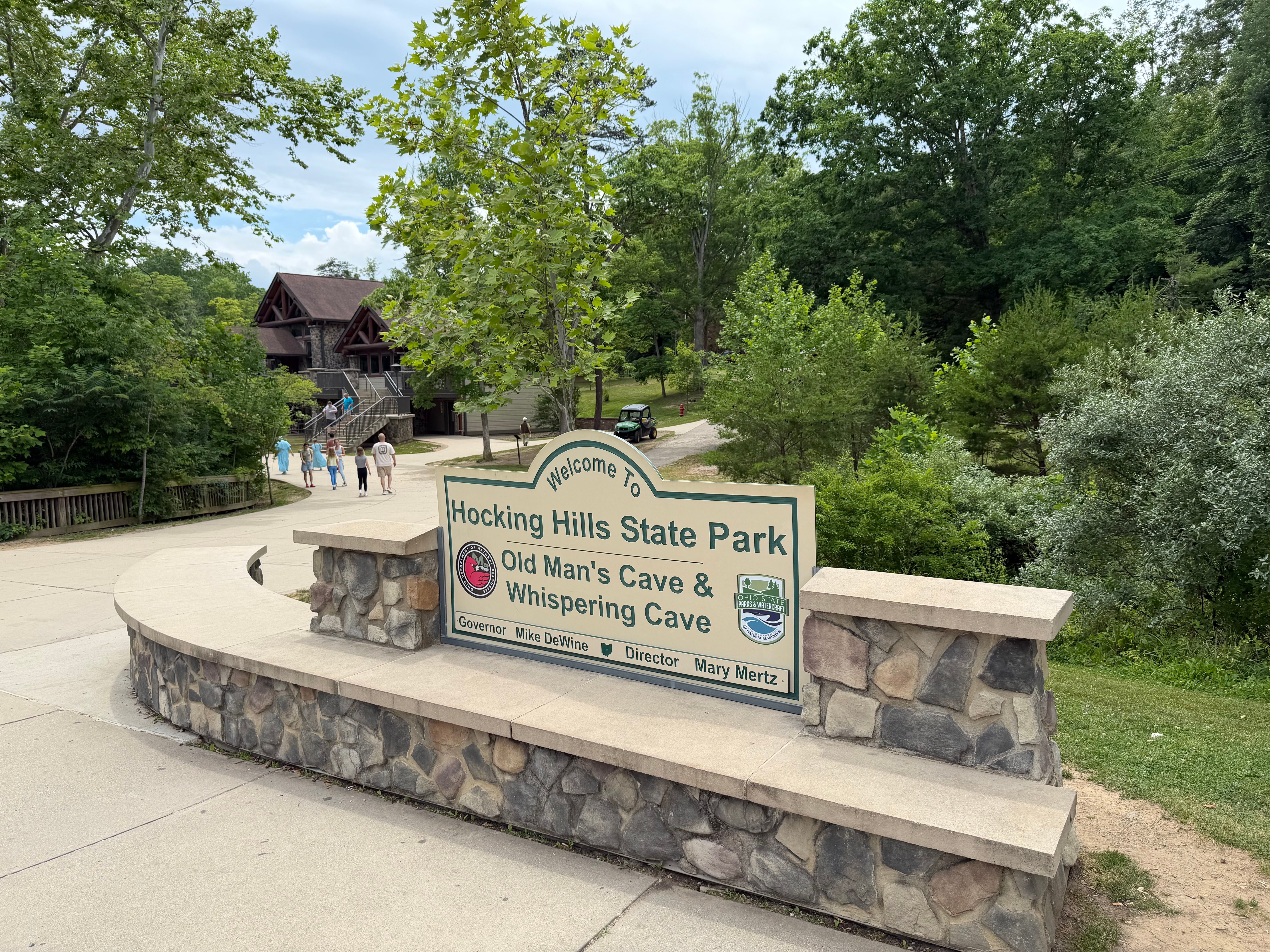 Entrance sign for Hocking Hills State Park’s Old Man’s Cave Visitor Center surrounded by trees and landscaped grounds.