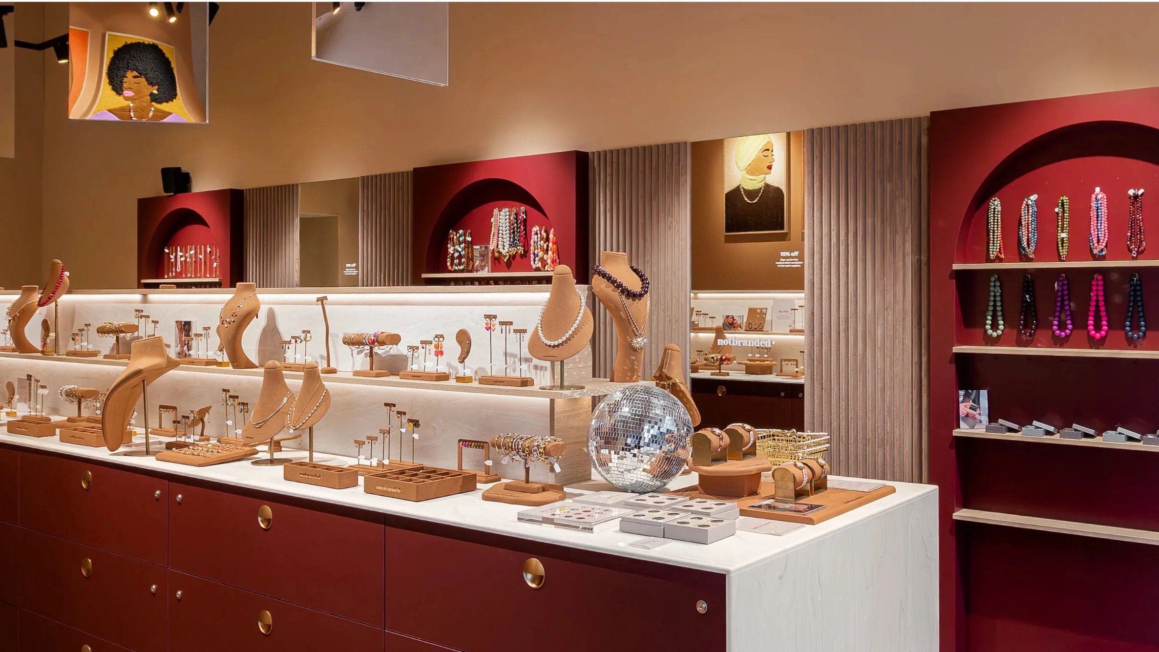 The Notbranded store interior, with jewelry displayed along the counter, arched wall niches of beaded necklaces, and a wall of loose beads