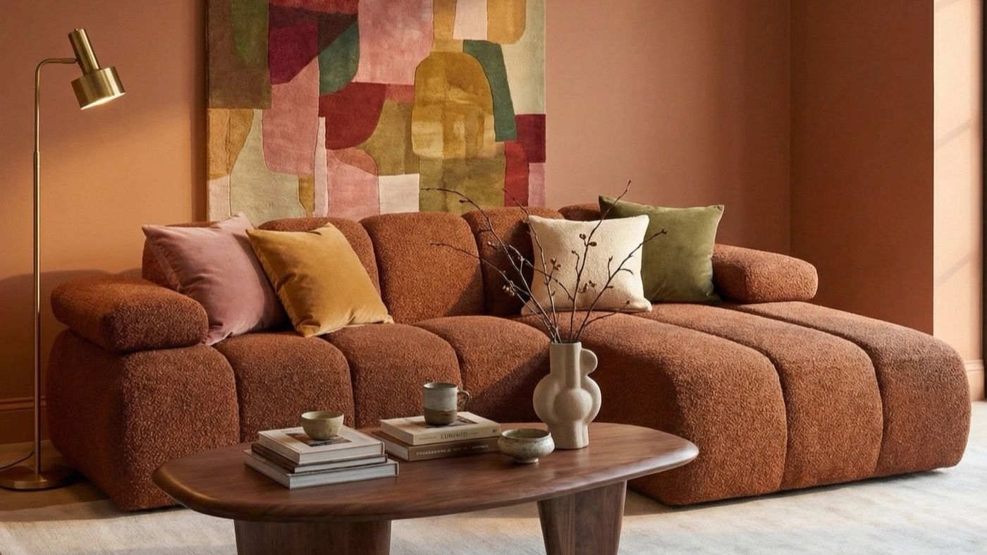 A WOOOD bouclé corner sofa in a warm terracotta living room, with a walnut coffee table