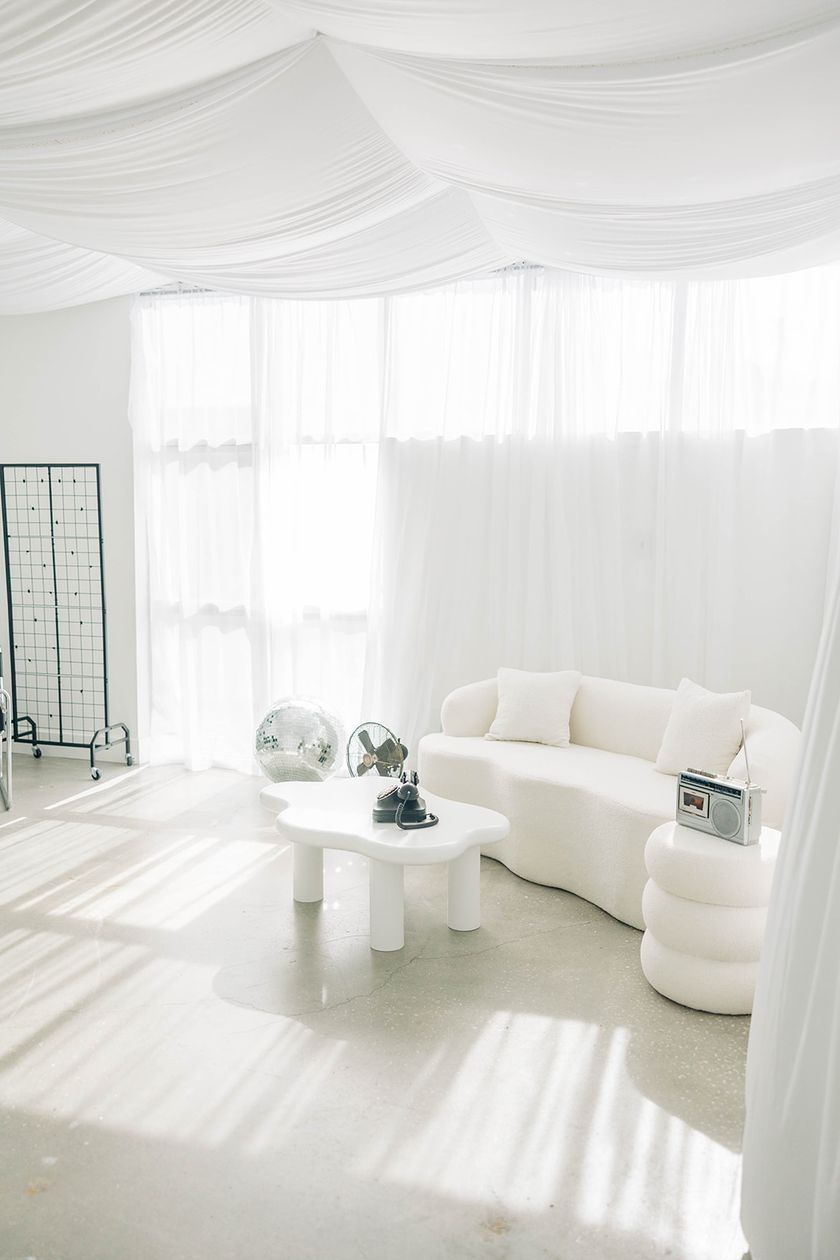 Studio B: morning light through sheer curtains onto the curved white sofa and concrete floors