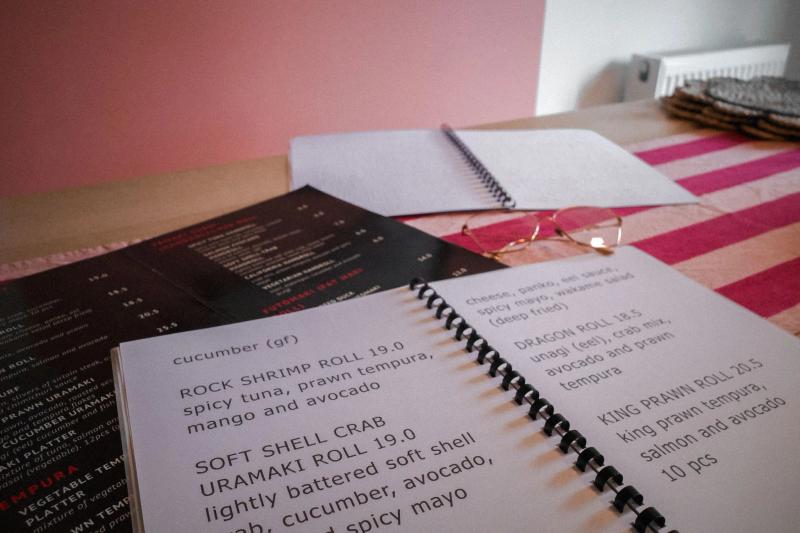 Large print menu laid on top of a standard version of the same menu on a desk