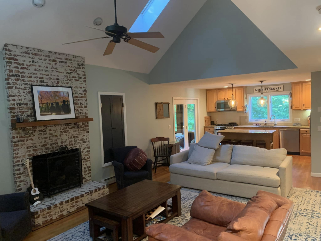 An open living room with vaulted ceiling and stone fireplace painted by Brookstone Painting and Carpentry in Plymouth County and Cape Cod
