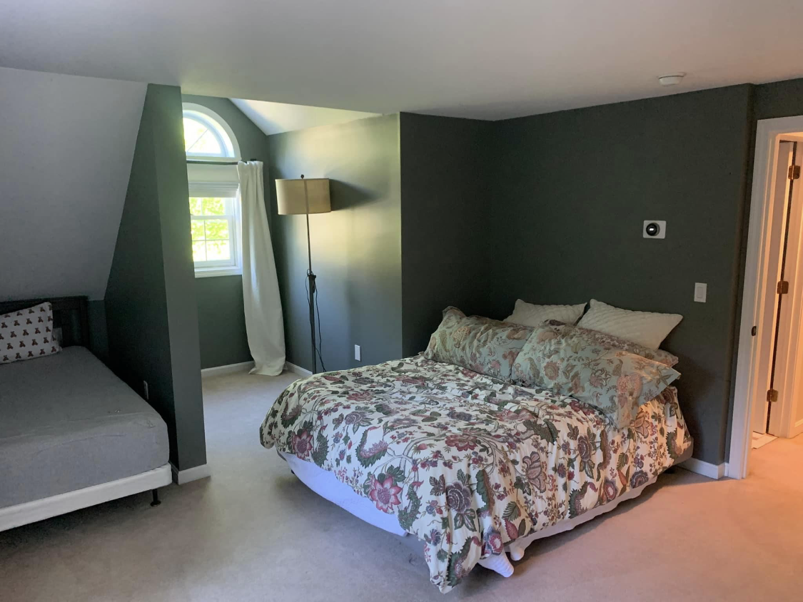 A bedroom with a dark green accent wall painted by Brookstone Painting and Carpentry in Plymouth County and Cape Cod