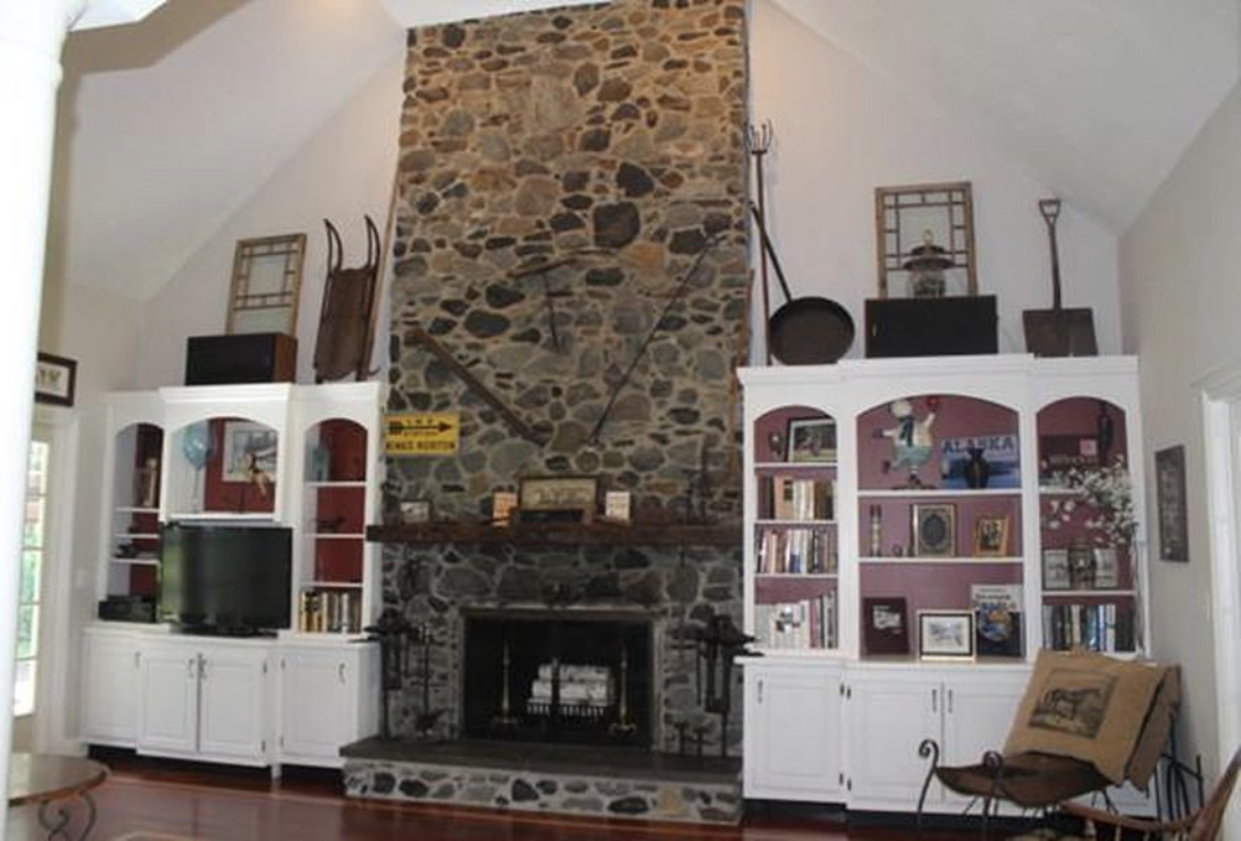 Painted white built-in cabinetry flanking a stone fireplace by Brookstone Painting and Carpentry in Plymouth County