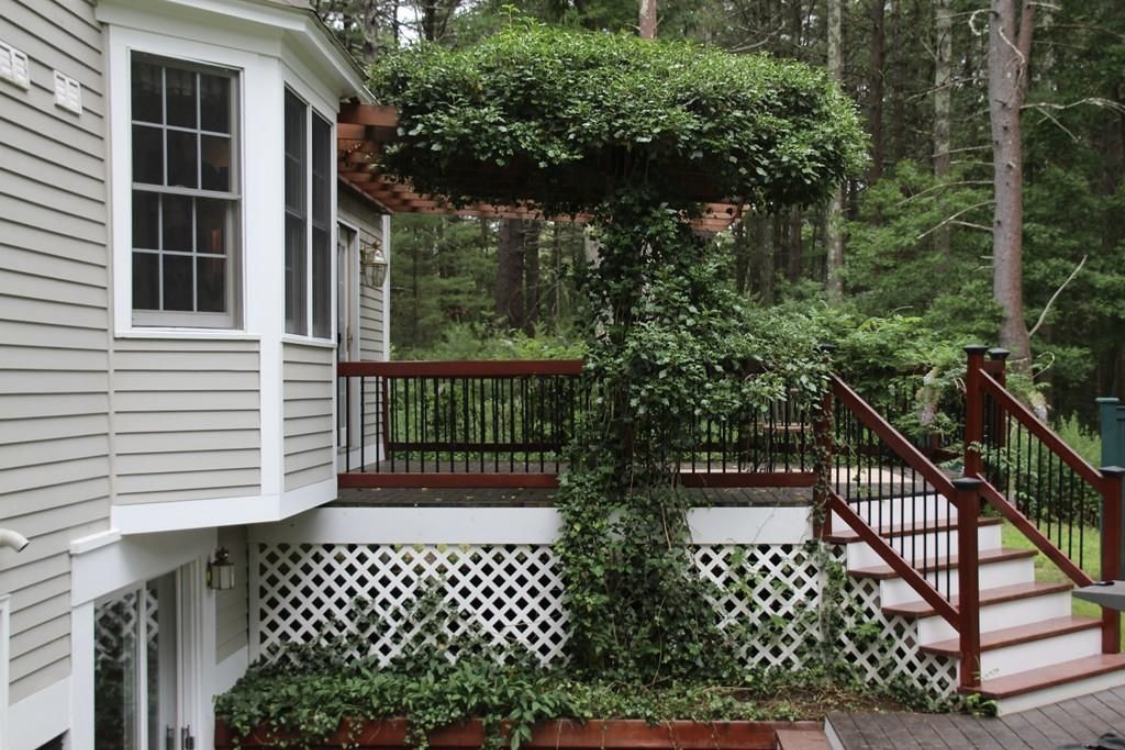 A raised deck with fresh dark stain and red-stained stairs by Brookstone Painting and Carpentry in Plymouth County