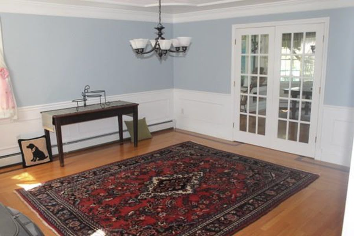 A dining room with blue walls, white wainscoting and chair rail painted by Brookstone Painting and Carpentry in Plymouth County and Cape Cod