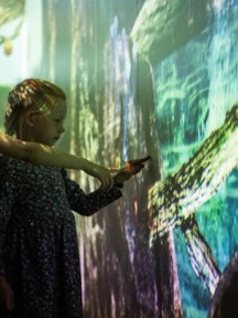 Barn som peker på interaktiv skjerm. Foto. Kreditering: Nasjonalmuseet