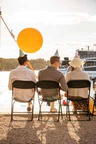 Tre bekkere med bursdagshatter i solnedgang. Foto.