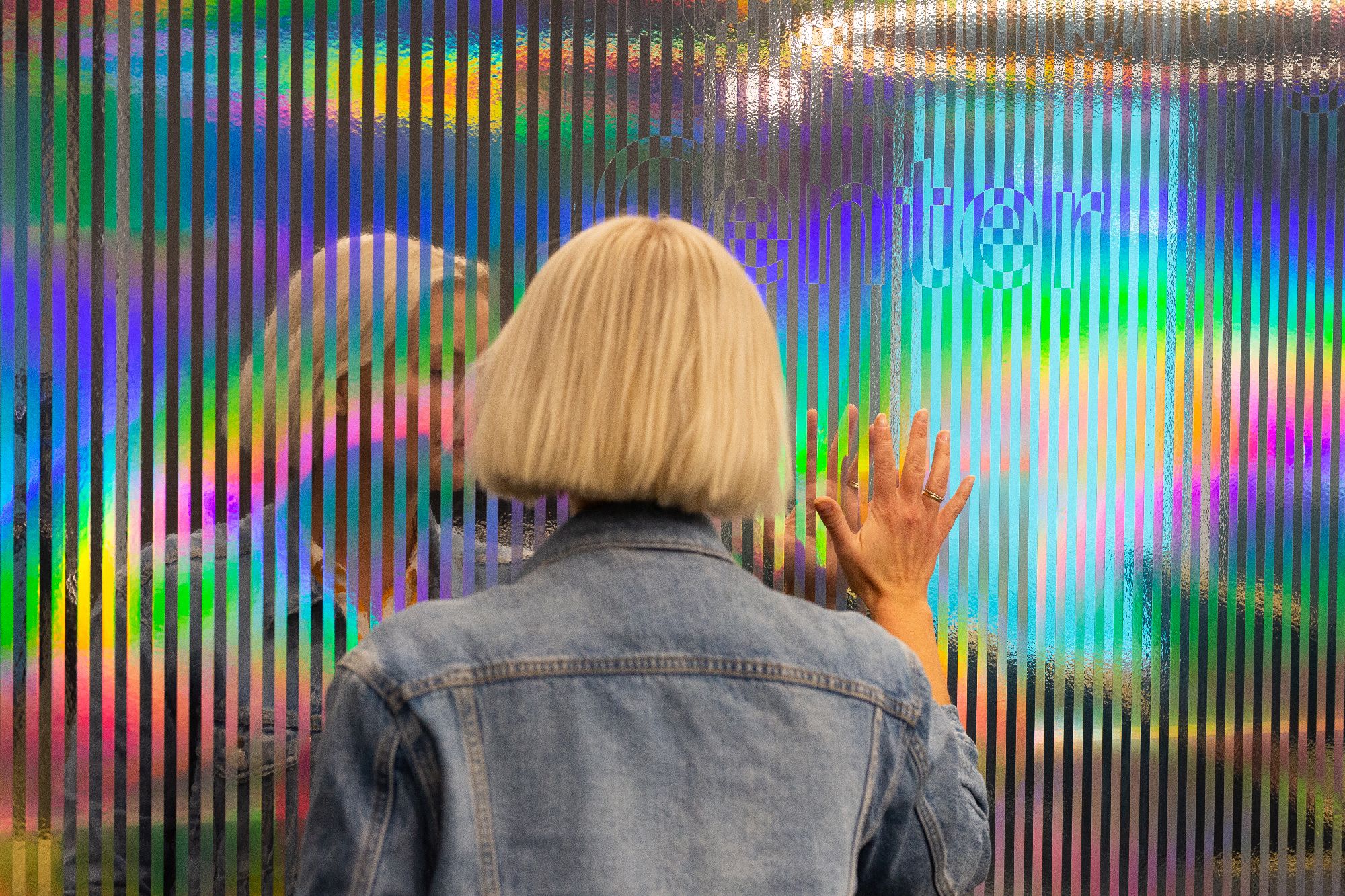 Dame speiler seg selv i installasjonsvegg for Microsoft. Foto.