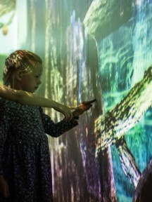 Barn som peker på interaktiv skjerm. Foto. Kreditering: Nasjonalmuseet