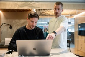 To designere som diskuterer foran laptop. Foto.