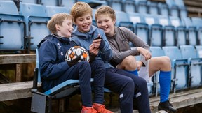 Tre gutter på fotballtrening som ser på telefon i hånda. Foto. Kreditering: Spleis