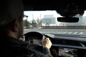 Mann som kjører bil foran Operaen. Foto.