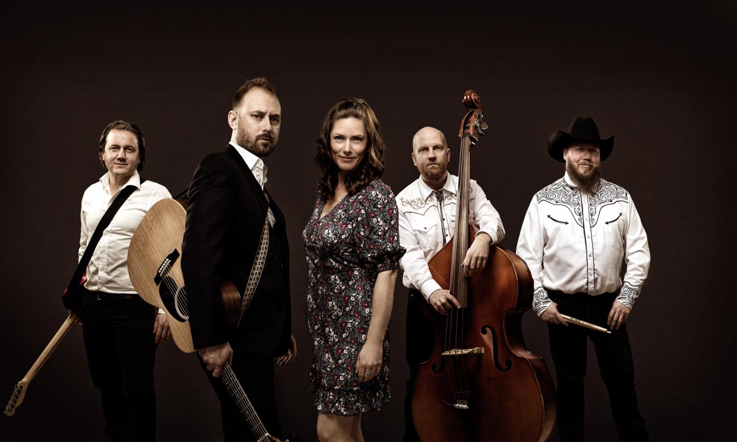Foto av musikere med instrumenter. Fire menn og en kvinne.