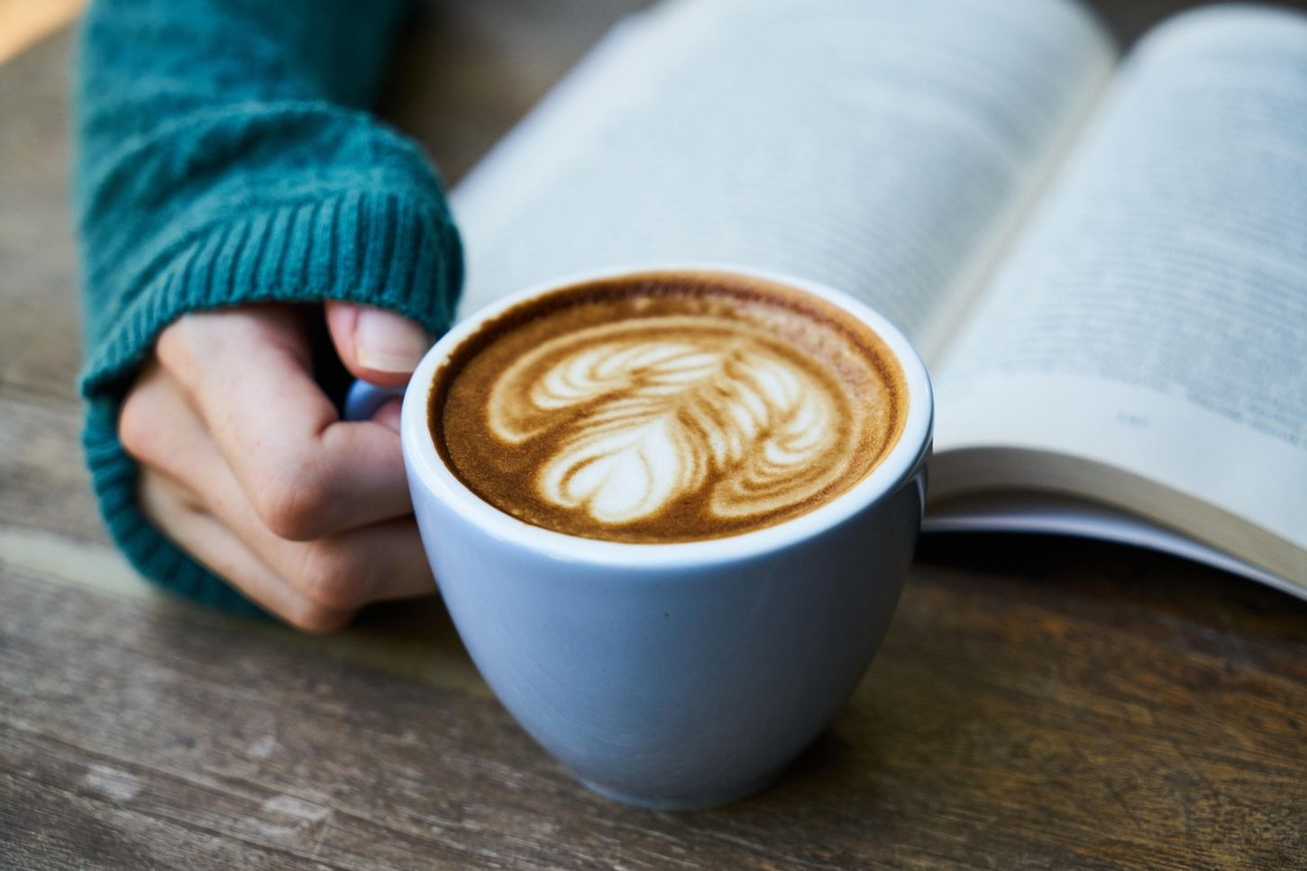 Bok og hånd med kaffekopp. Foto: Pixabay