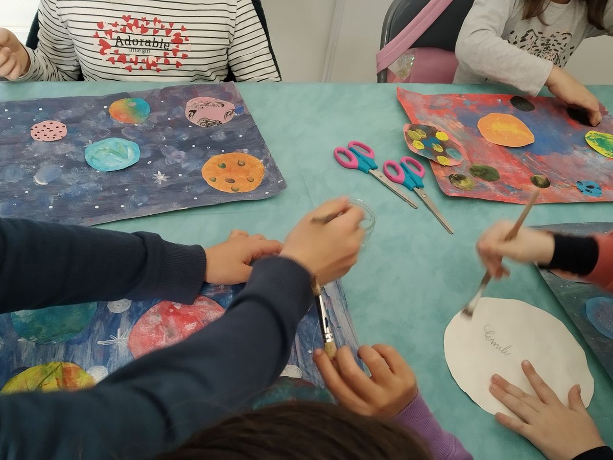 Des enfants peignent ensemble sur la grande table de l'atelier