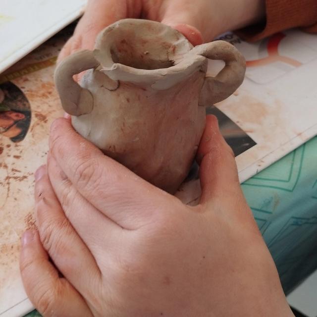 Un pot à anses en argile, tenu dans les mains