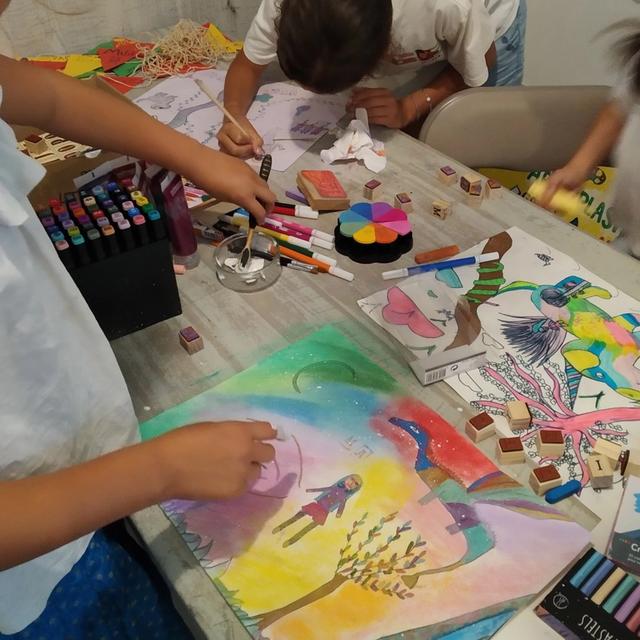 Des enfants dessinent aux pastels sur une grande feuille