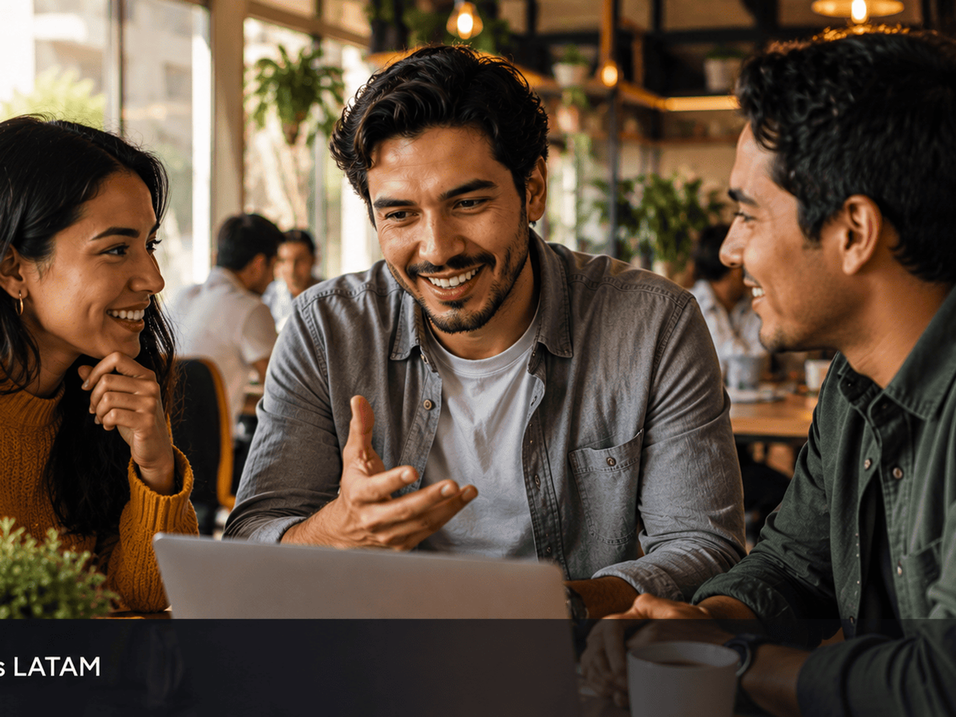 Grupo de jovenes latinoamericanos colaborando alrededor de laptop en coworking representando el poder de las comunidades.