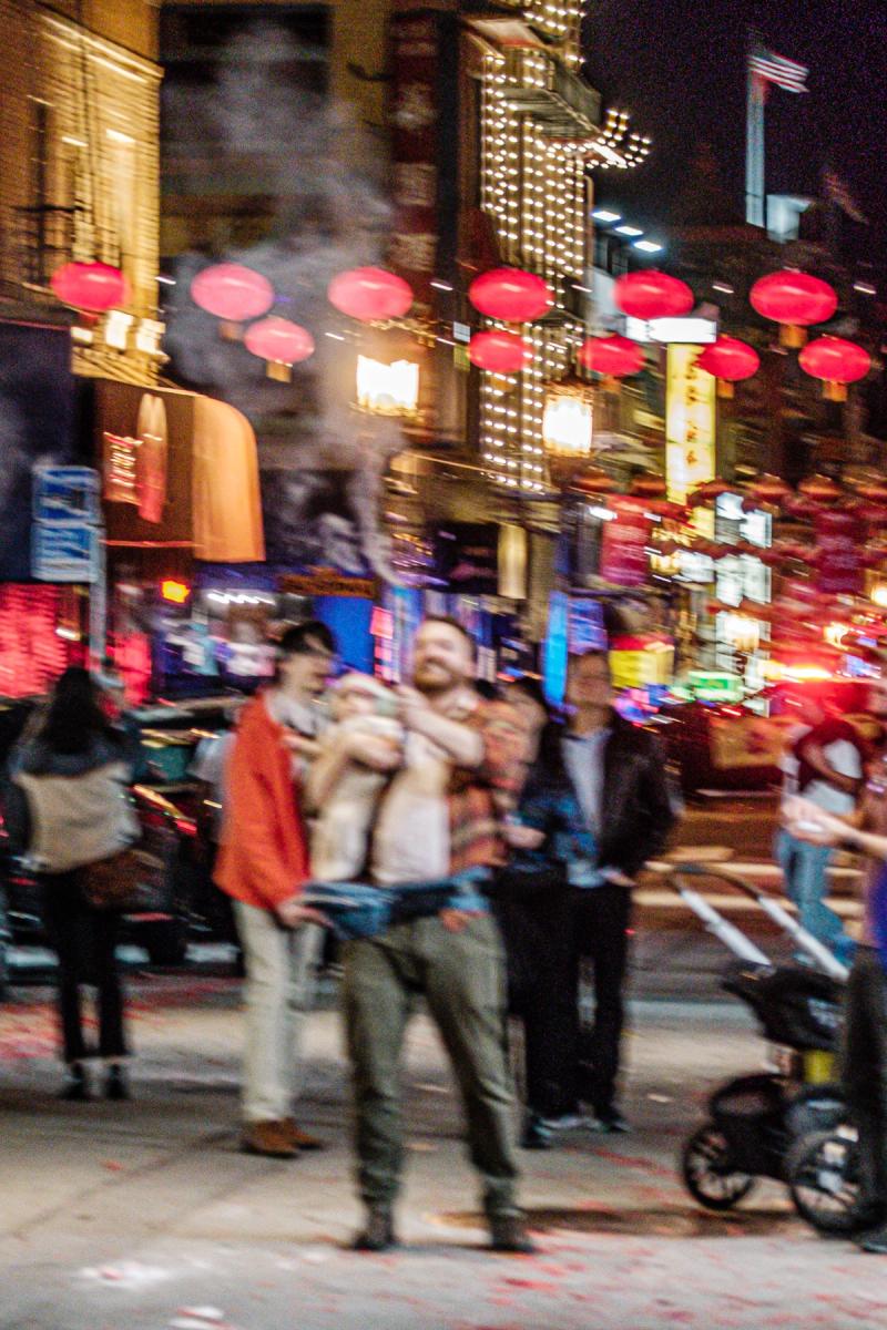 I guy with baby in a sling firing off roman candles