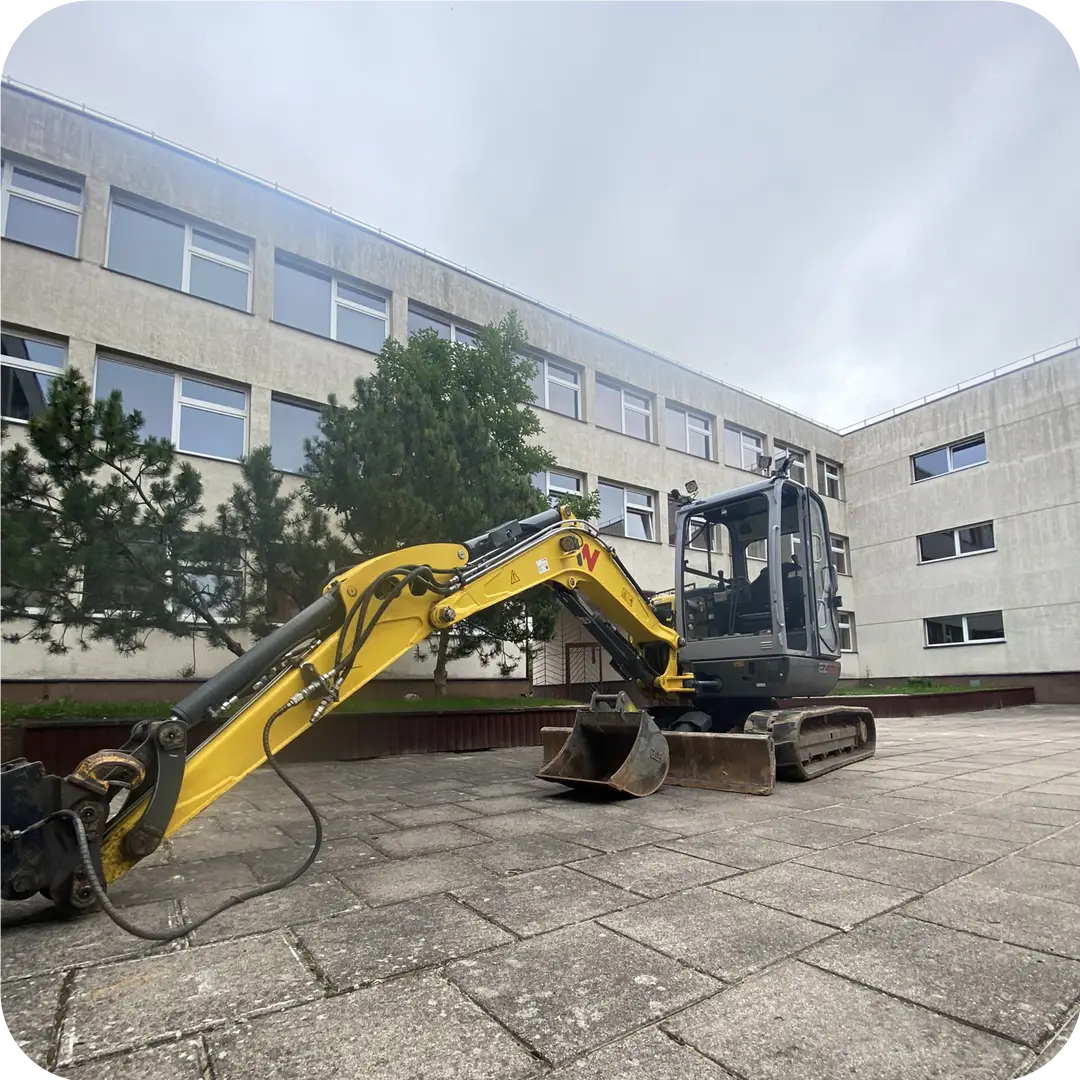 Wacker Neuson ekskavatorius aplinkos tvarkymo darbuose prie visuomeninio pastato