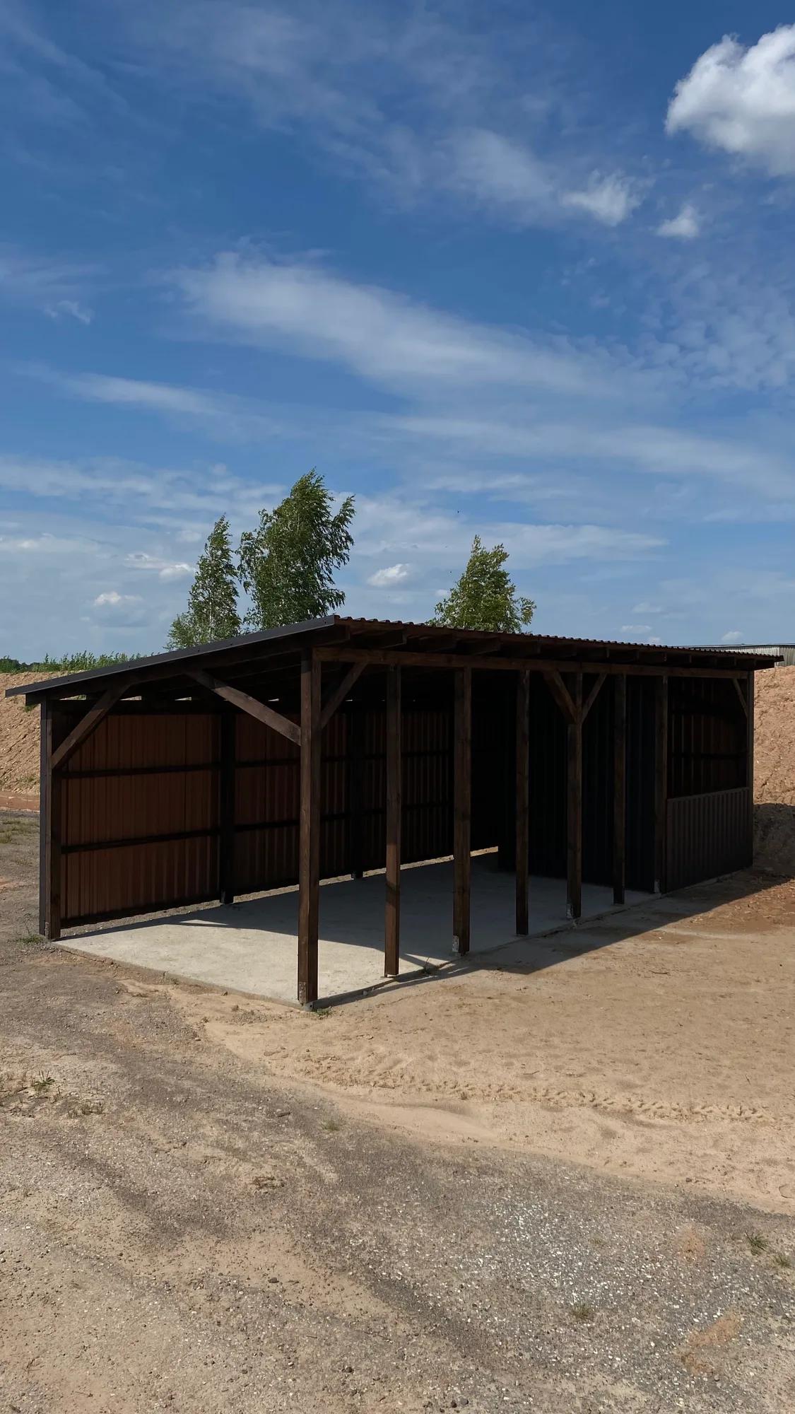Didelė medinė pavėsinė-pastogė su skardos sienomis ant betoninio pagrindo