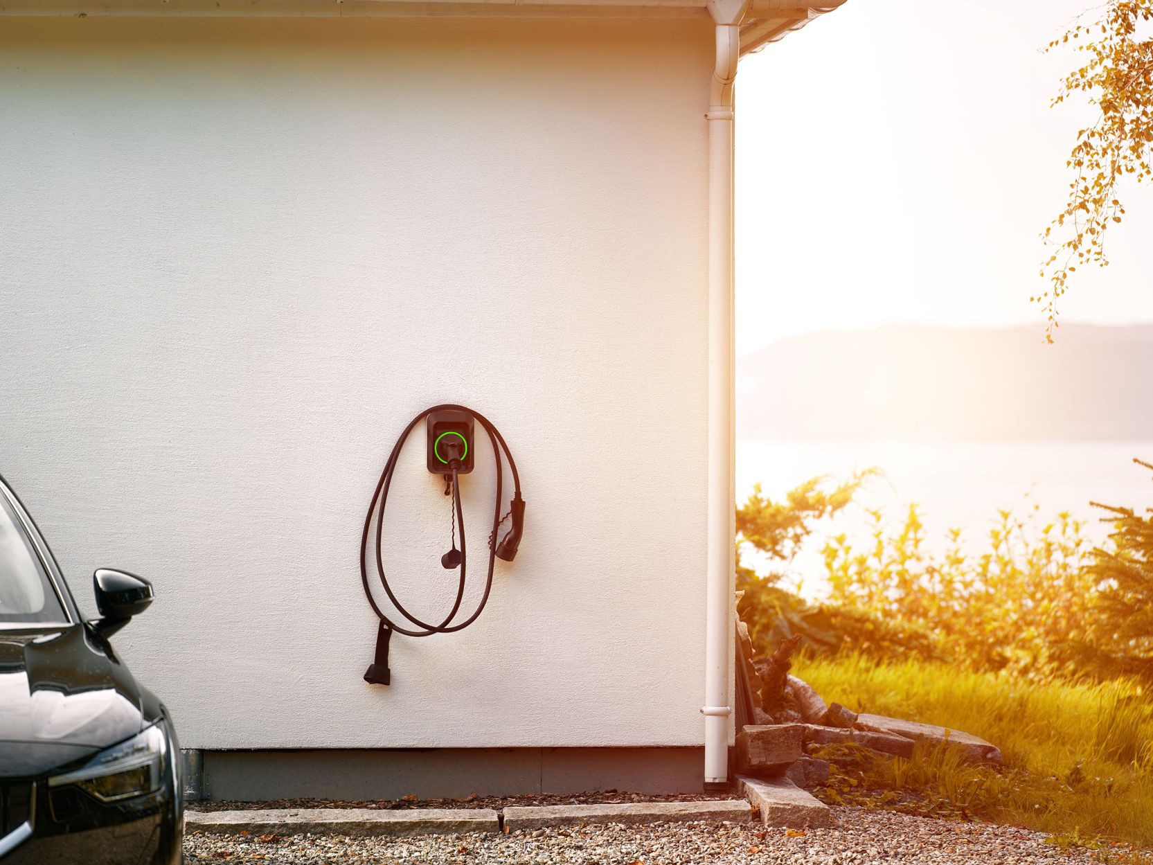 parkerad bil med laddstation på väggen.