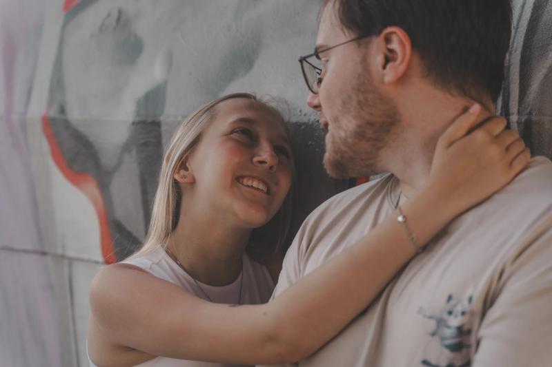 Eine Frau und ein Mann stehen eng umschlungen vor einer Wand.