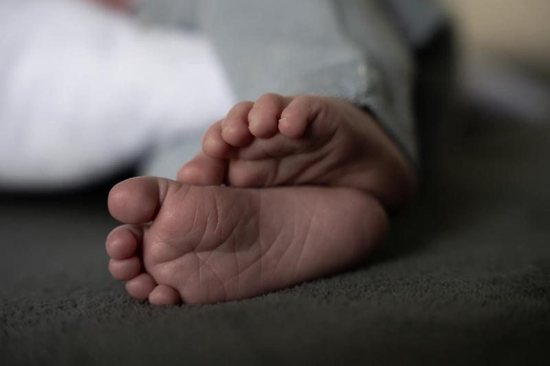 Nahaufnahme kleiner Babyfüße, behutsam von einer Hand gehalten.
