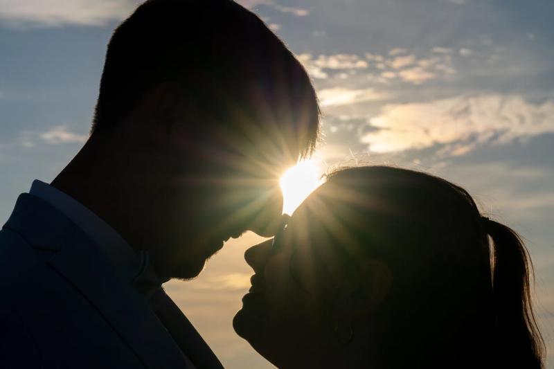 Die Silhouetten eines Paares berühren sich im warmen Sonnenlicht.