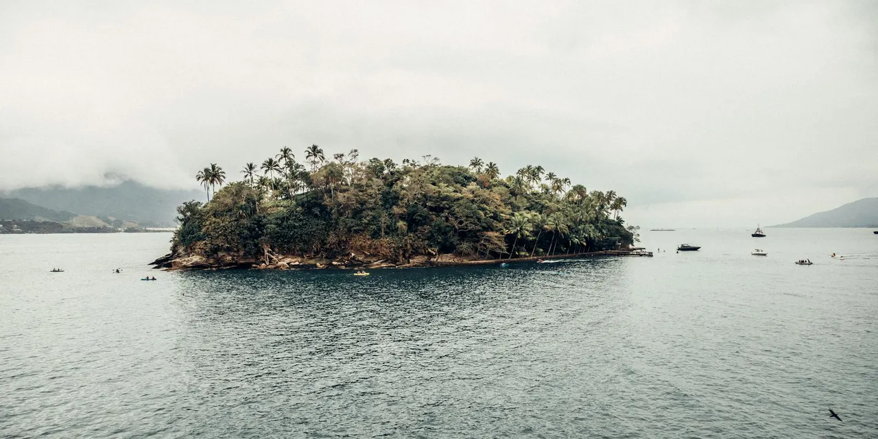 Explore the serene beauty of Cabras Island off Ilhabela's coastline with boats and lush foliage.