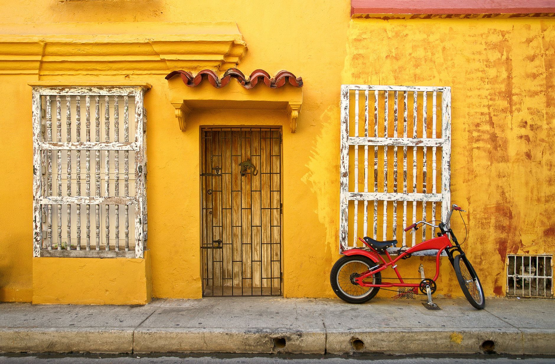 Vibrant yellow wall and rustic architecture with a red bike in Cartagena, Colombia.