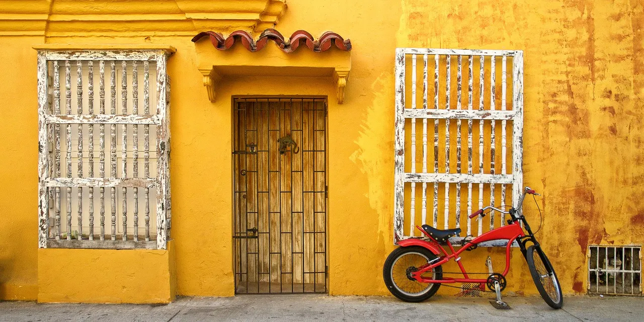 Vibrant yellow wall and rustic architecture with a red bike in Cartagena, Colombia.