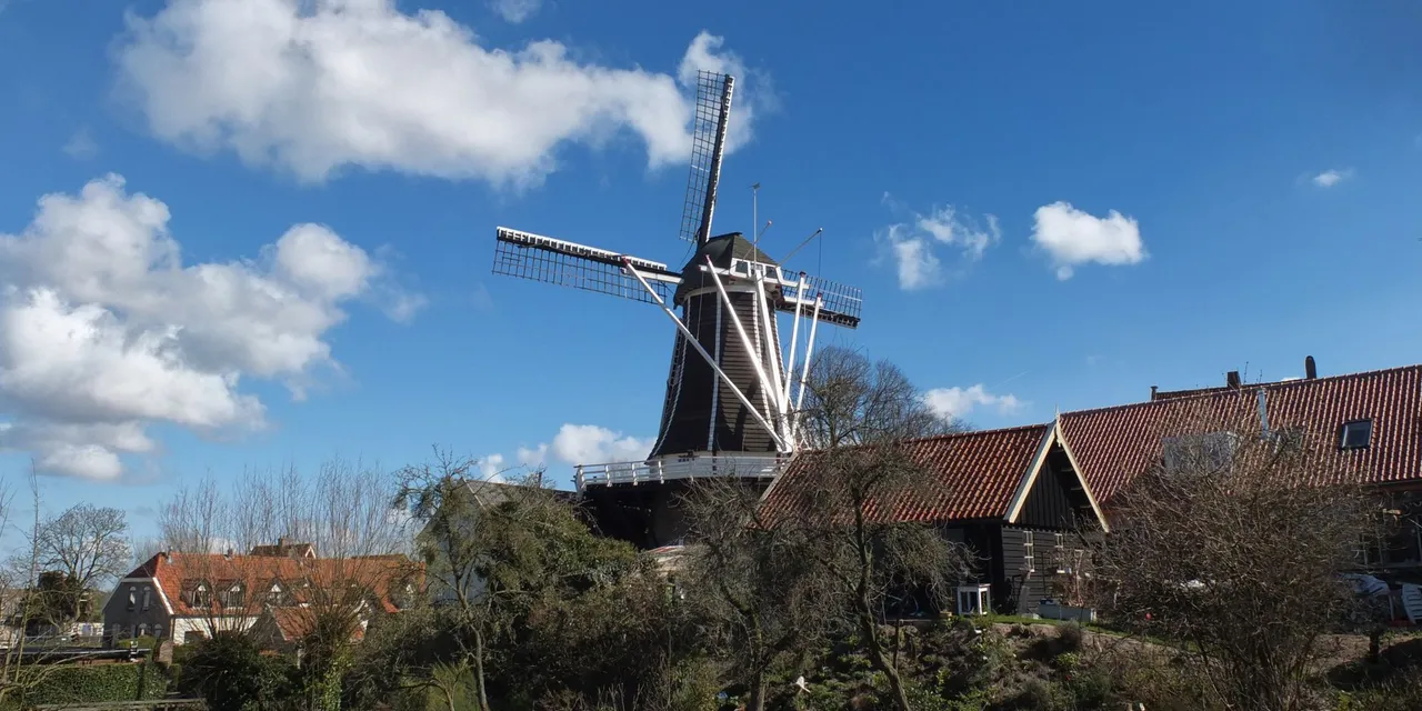 A scenic view of a traditional windmill in Hattem, Gelderland on a sunny day.