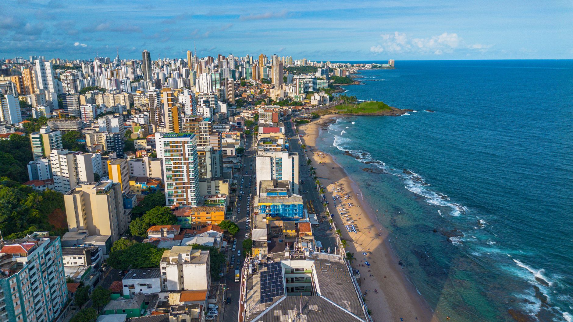 A breathtaking aerial view of Salvador, featuring the bustling cityscape alongside the tranquil beach and blue ocean.