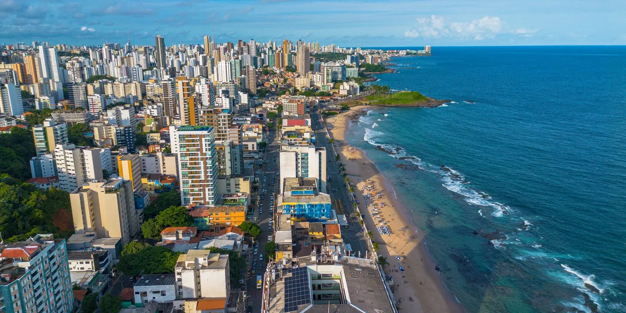 A breathtaking aerial view of Salvador, featuring the bustling cityscape alongside the tranquil beach and blue ocean.